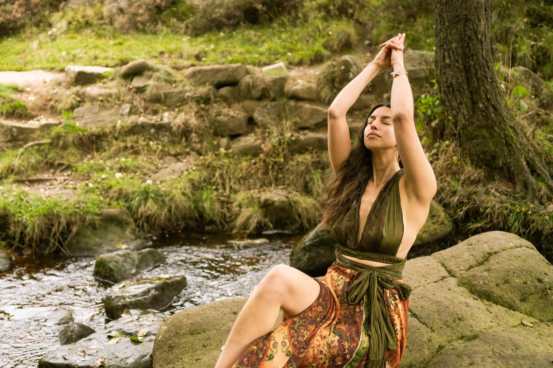 Woman in ritual dress by a woodland stream